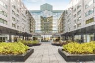 Véritable respiration au cœur de l’hôtel, la cour intérieure offre un cadre calme et lumineux, baigné de lumière naturelle grâce à l’immense verrière centrale. Un espace aéré, végétalisé et apaisant, idéal pour une pause, un cocktail ou des échanges infor | © Hilton Roissy Charles de Gaulle