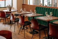 Dans la salle du Café Almanach, murs aux teintes chaudes, luminaires en laiton patiné et tables en bois massif créent une ambiance feutrée. Banquettes velours, tapis orientaux et œuvres d’art chinées ponctuent l’espace d’une atmosphère à la fois convivial | © L'Almanach Montmartre