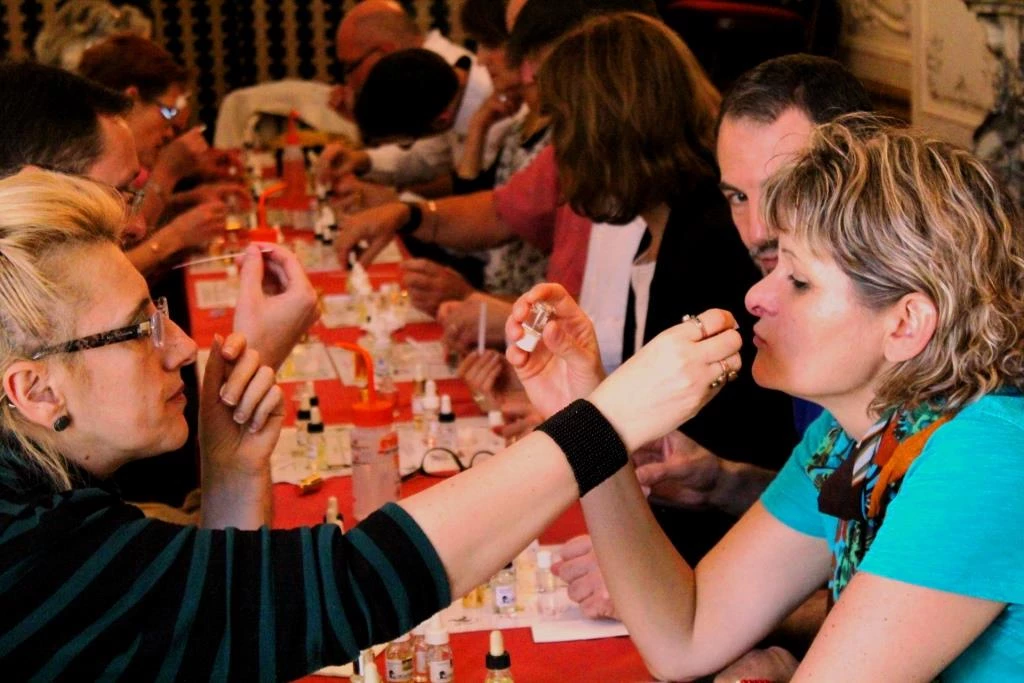 Groupe de salariés participant à un team building de création de parfums autour d'une table.