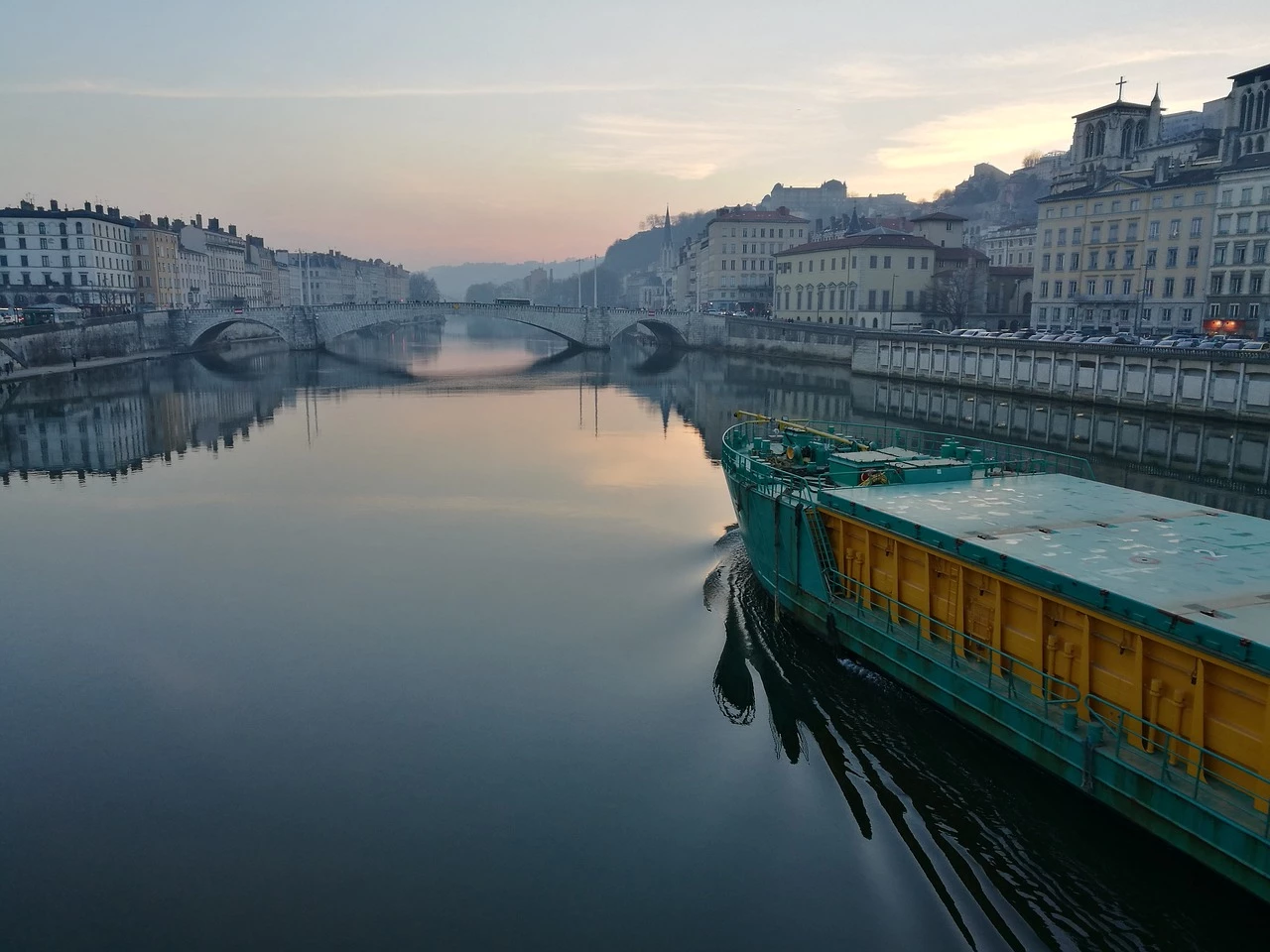 Bateau s'apprêtant à passer sous un pont en fin de journée à Lyon.