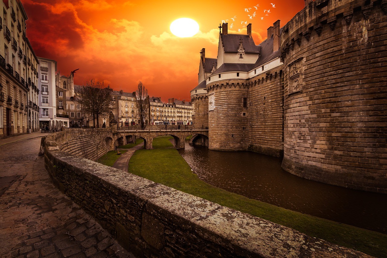 Château des ducs de Bretagne de Nantes éclairé par un coucher de soleil orangé.
