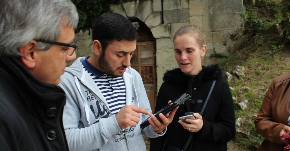 Groupe de salariés cherchant des indices sur une tablette lors d'un team building rallye interactif.