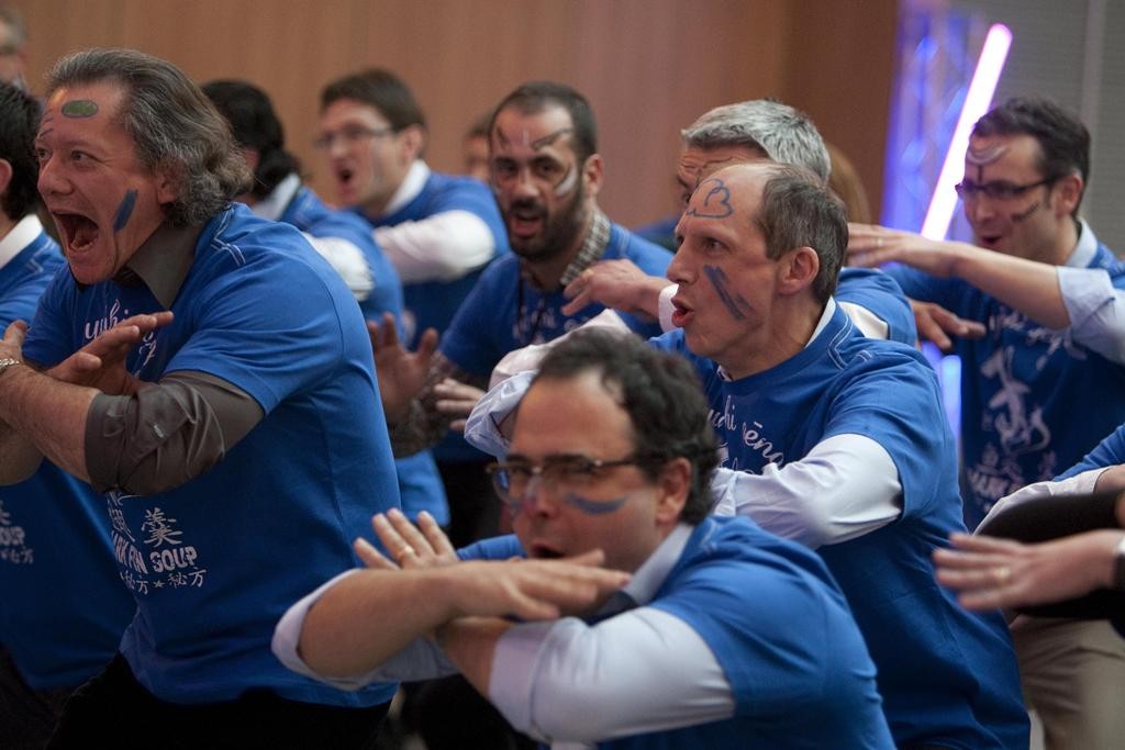 Groupe de salariés maquillés participants à un haka lors d'un team building.